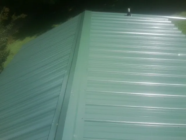New green metal panels meeting at the ridge of a roof — Flat Roof Repair work by our crew in Iona