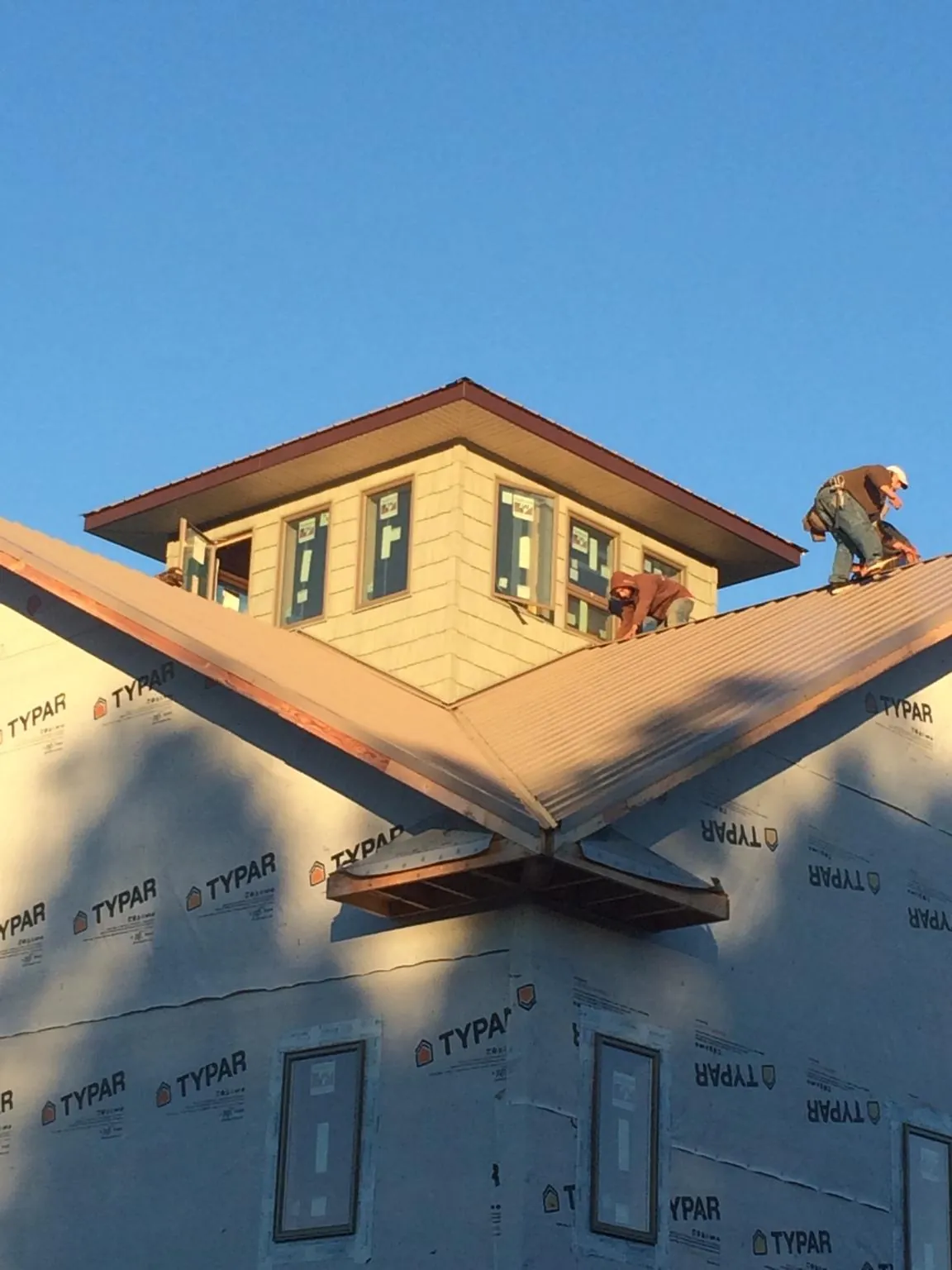 Roofers working around a rooftop cupola on a new metal roof at sunset — Roof Waterproofing in Iona by Roofing Brothers
